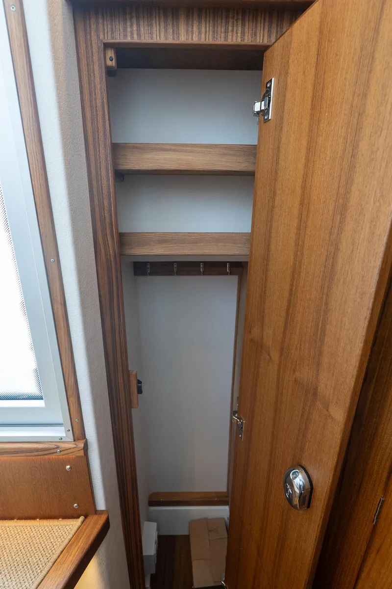 Slide: The Image of Wooden storage cabinet inside 2025 Targa 32 GT boat, featuring shelves and hooks. - 47