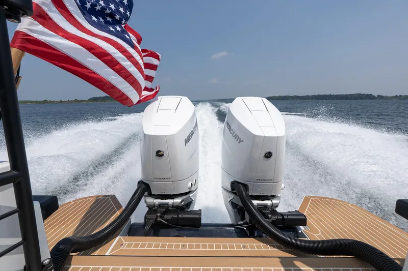 Slide: The Image of 2025 Targa 32 GT boat with dual Mercury engines and American flag on open water. - 7