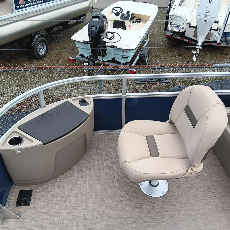 Slide: The Image of 2025 Sun Tracker Bass Buggy 18 DLX pontoon boat interior with beige seating and console. - 10
