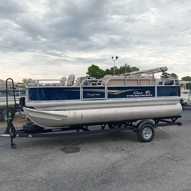 Slide: The Image of 2025 Sun Tracker Bass Buggy 18 DLX pontoon boat on trailer, parked outdoors. - 4