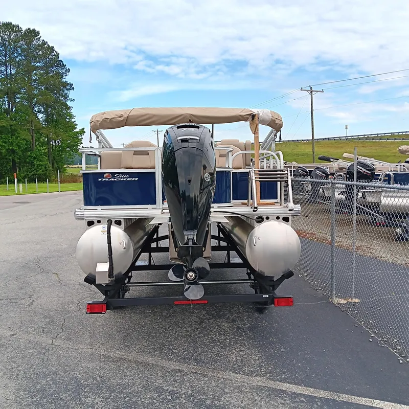 Slide: The Image of 2025 Sun Tracker Bass Buggy 18 DLX pontoon boat with outboard motor, parked on trailer. - 6
