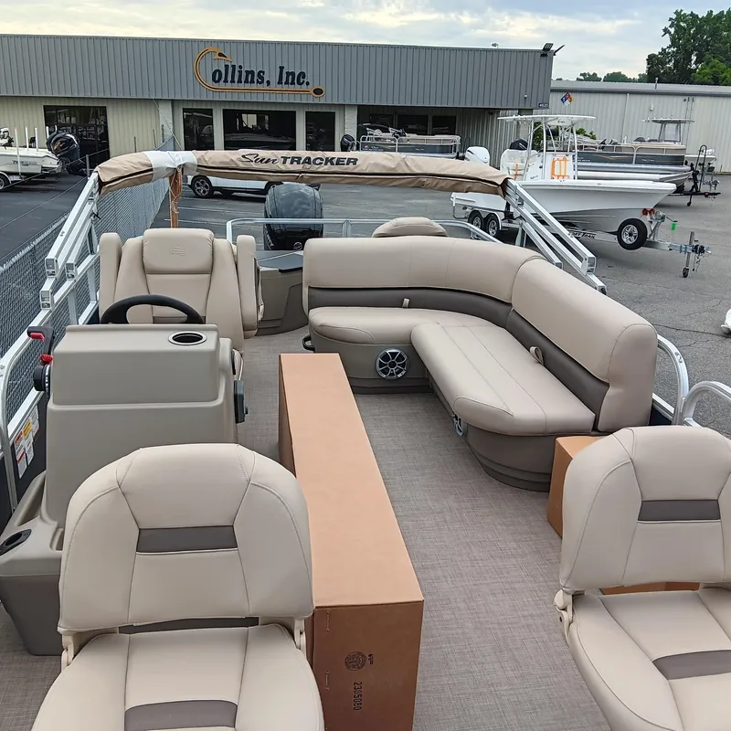 Slide: The Image of 2025 Sun Tracker Bass Buggy 18 DLX pontoon boat with beige seating at dealership. - 9