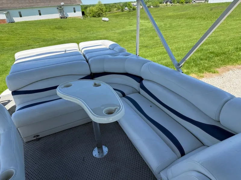 Slide: The Image of 2006 Bennington 2575 RFS - IO boat interior with white seating and table, grassy background. - 5