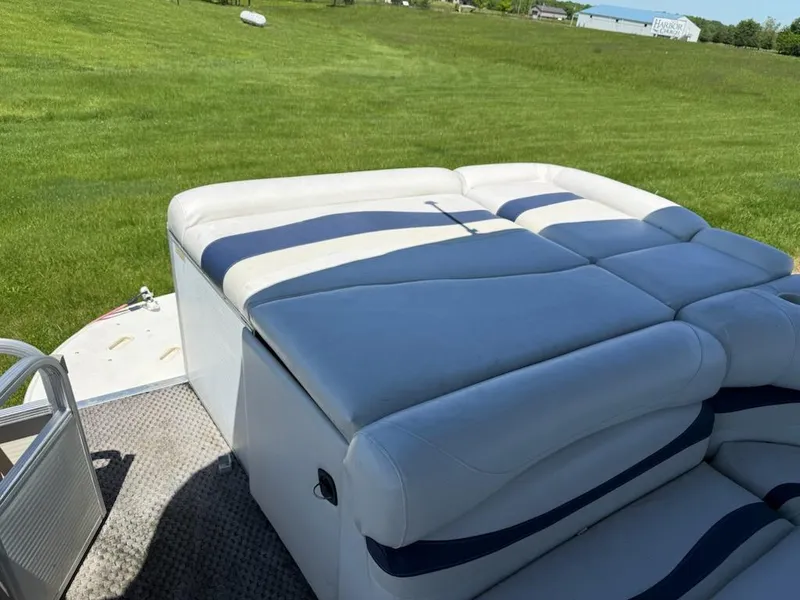 Slide: The Image of 2006 Bennington 2575 RFS - IO boat with white and blue seating on grassy field. - 9