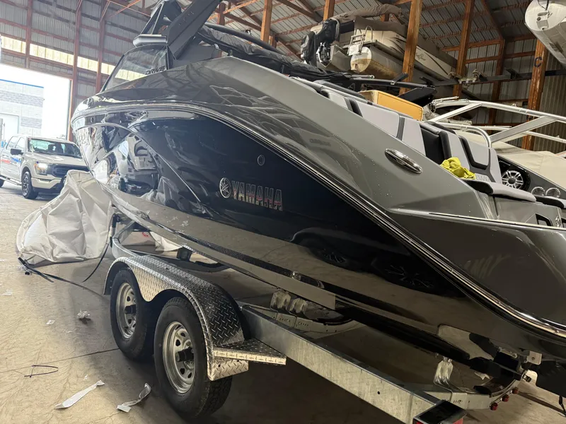 Slide: The Image of 2025 Yamaha Boats 222XD in a warehouse, sleek black design on a trailer. - 1