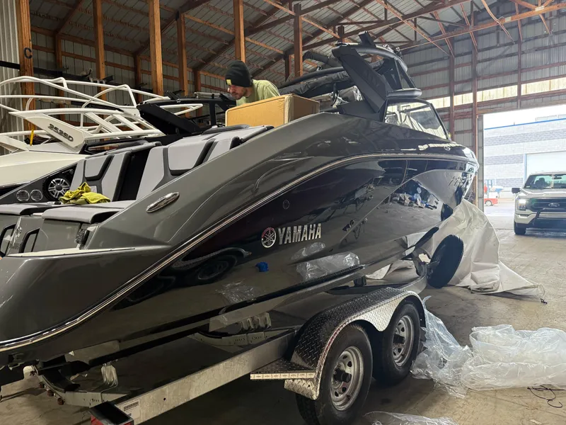 Slide: The Image of 2025 Yamaha Boats 222XD on trailer in warehouse, sleek design, black finish. - 2