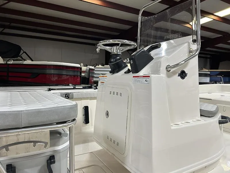 Slide: The Image of 2025 Carolina Skiff 21 LS boat interior with steering console and seating in a storage facility. - 10