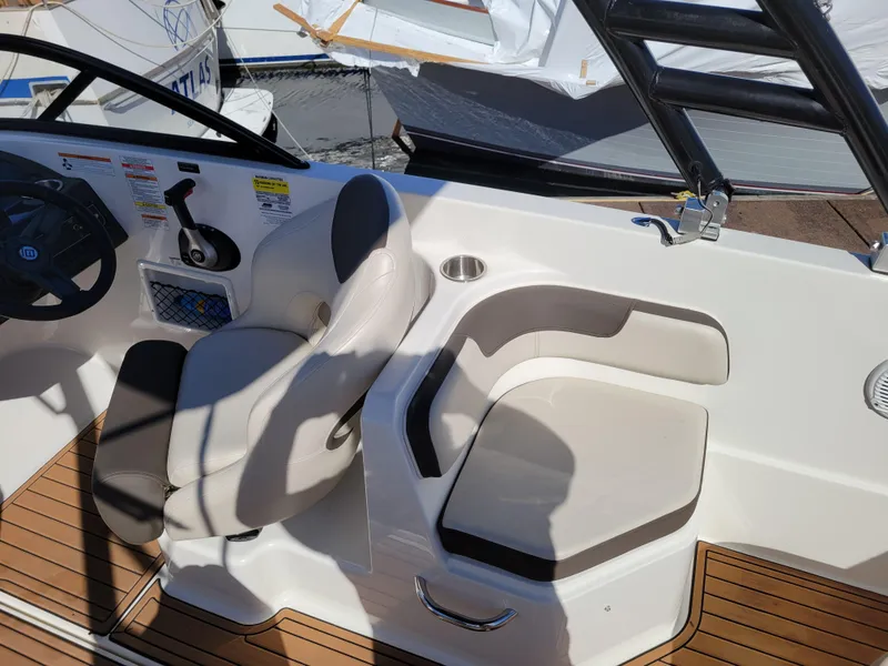 Slide: The Image of 2019 Bayliner VR6 Bowrider I/O interior with seating and steering wheel, docked at marina. - 14