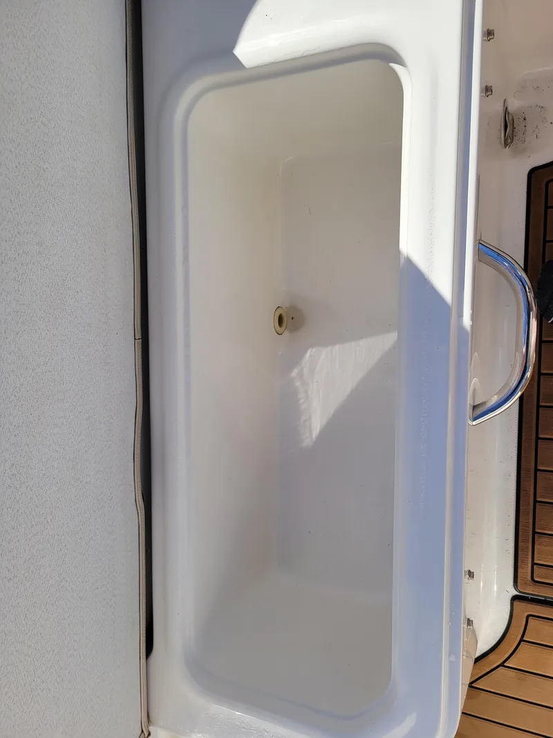 Slide: The Image of 2019 Bayliner VR6 Bowrider I/O storage compartment, white interior, with drain plug. - 34