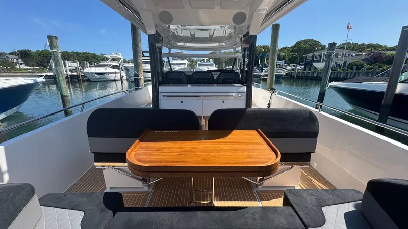 Slide: The Image of Nimbus T11 2025 boat interior with wooden table, black seating, docked at marina. - 16