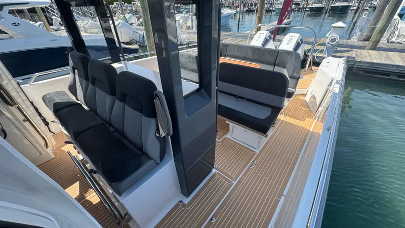 Slide: The Image of Modern Nimbus T11 boat interior with sleek seating, wood flooring, and marina backdrop, 2025 model. - 26