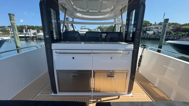 Slide: The Image of Nimbus T11 2025 boat interior with seating and storage, docked at a marina. - 17