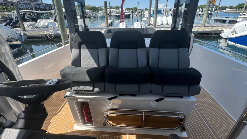 Slide: The Image of Three cushioned seats on a 2025 Nimbus T11 boat, docked at a marina. - 20