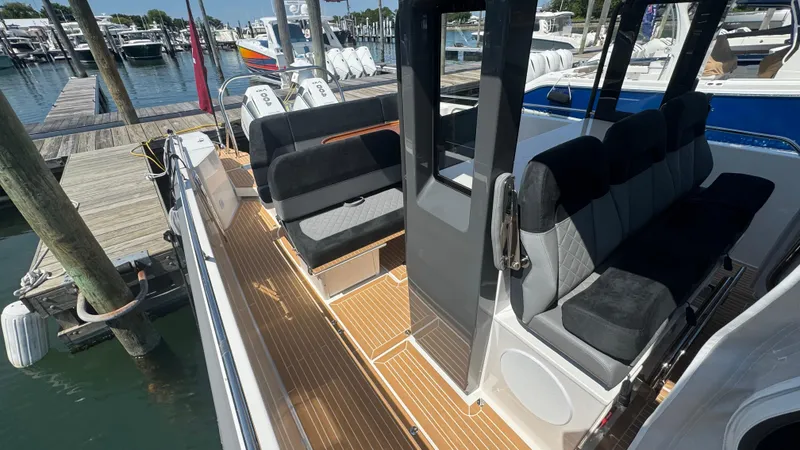 Slide: The Image of Modern Nimbus T11 boat interior with sleek seating and wooden deck, docked at a marina. - 23