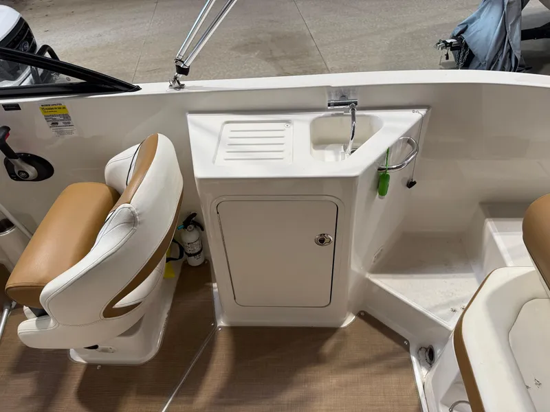 Slide: The Image of 2021 Bayliner DX2250 boat interior with sink, storage, and seating area. - 6