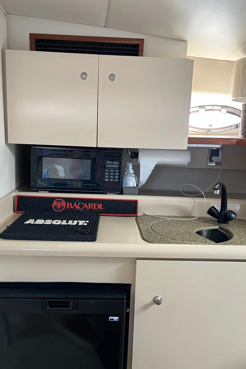 Slide: The Image of 2001 Cruisers Yachts 2870 Express interior kitchen with microwave, sink, and storage cabinets. - 30