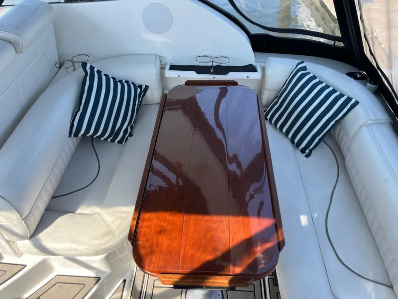 Slide: The Image of 2001 Cruisers Yachts 2870 Express interior with polished wood table and striped cushions. - 8