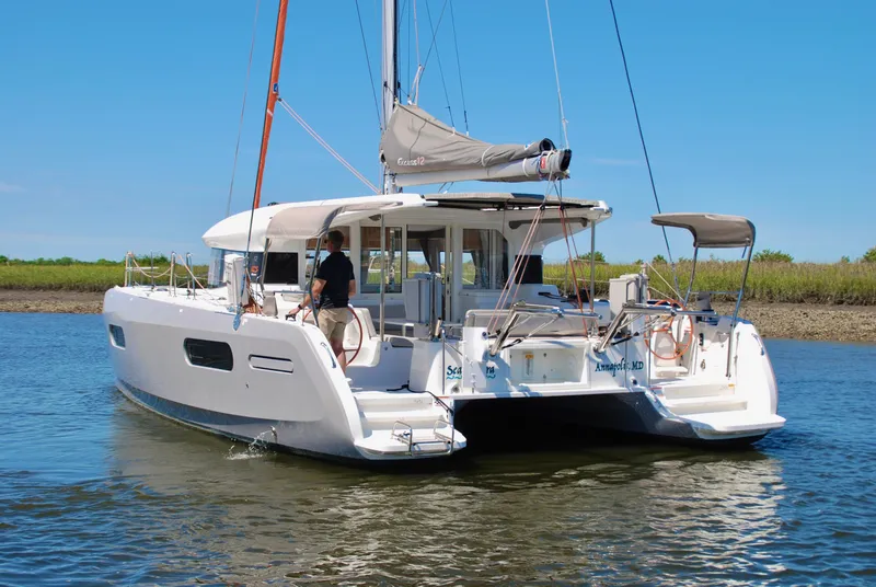 Slide: The Image of 2023 Excess 12 catamaran sailing on calm waters under a clear blue sky. - 2