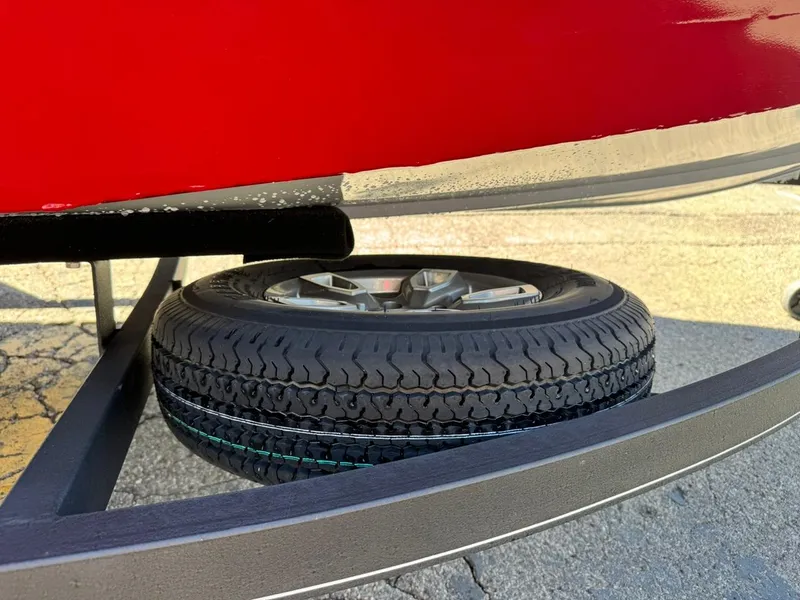 Slide: The Image of 2022 Tracker PRO TEAM 175 TWX boat trailer with spare tire, red hull visible. - 21