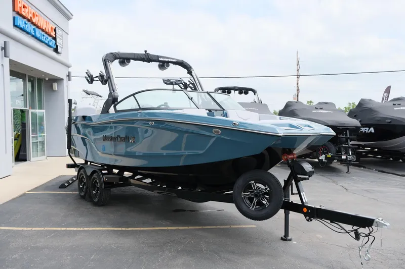 Slide: The Image of 2025 MasterCraft XT24 boat on trailer outside marine dealership. - 13