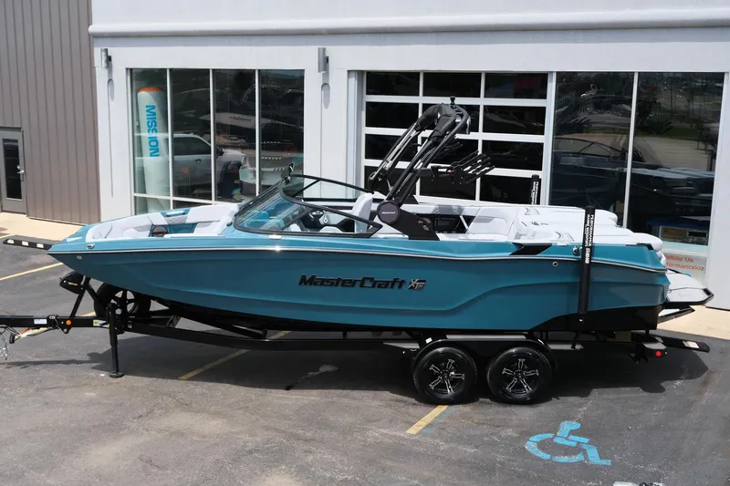 Slide: The Image of 2025 MasterCraft XT24 boat in blue on a trailer, parked outside a showroom. - 3