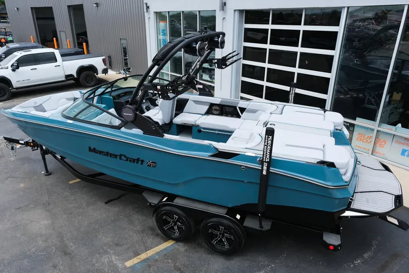 Slide: The Image of 2025 MasterCraft XT24 boat in blue, parked on a trailer outside a showroom. - 4