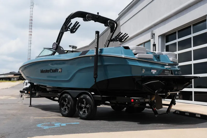 Slide: The Image of 2025 MasterCraft XT24 boat on trailer, parked outside a building. - 7