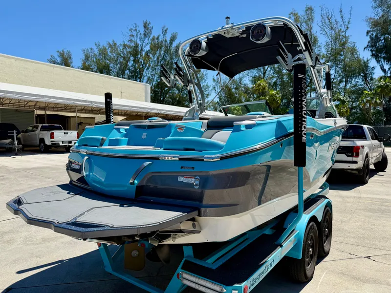 Slide: The Image of 2019 MasterCraft X22 boat on trailer, vibrant blue and gray, parked outdoors. - 2