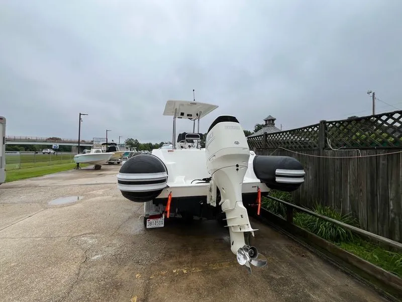 Slide: The Image of 2019 Apex A-24 boat with outboard motor on a trailer, parked on a cloudy day. - 2