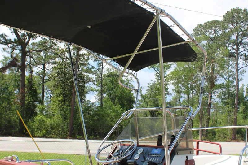 Slide: The Image of 1982 Boston Whaler 17 Montauk boat with canopy and steering console, parked near trees. - 18