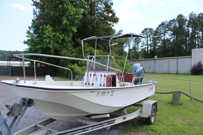 Slide: The Image of 1982 Boston Whaler 17 Montauk boat on trailer, parked outdoors near trees and building. - 5