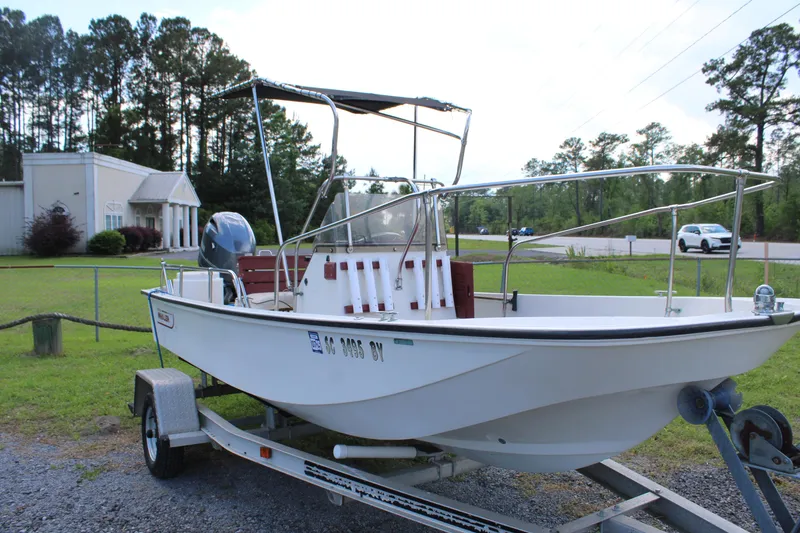 Slide: The Image of 1982 Boston Whaler 17 Montauk boat on trailer, parked outdoors near trees and buildings. - 6