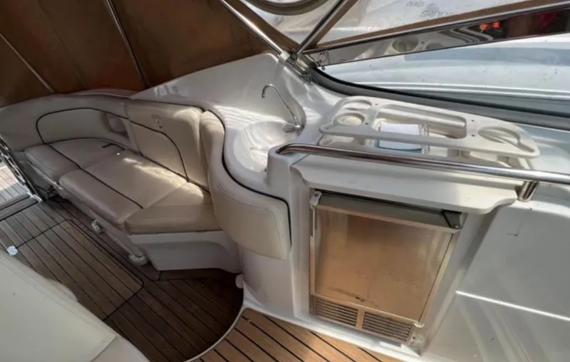Slide: The Image of 2004 Chris-Craft 33 Express interior with seating, sink, and mini-fridge on teak flooring. - 11