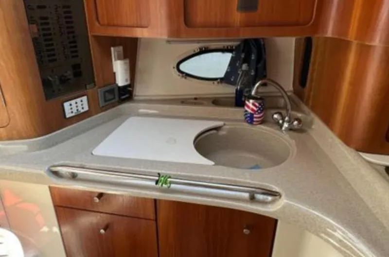 Slide: The Image of 2004 Chris-Craft 33 Express yacht kitchen with sink, wooden cabinets, and countertop. - 28