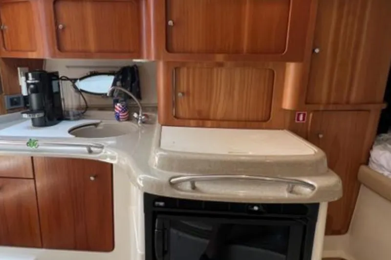 Slide: The Image of 2004 Chris-Craft 33 Express yacht kitchen with wooden cabinets and modern appliances. - 32