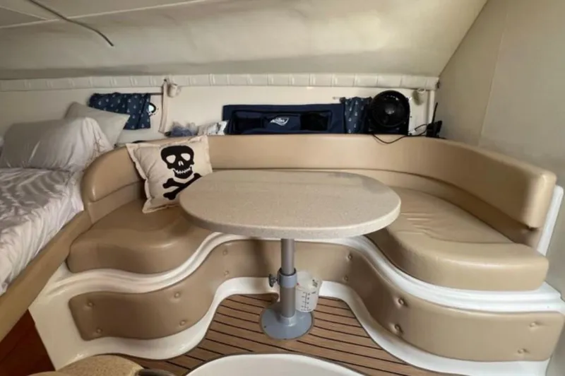 Slide: The Image of 2004 Chris-Craft 33 Express cabin interior with beige seating, table, and skull pillow. - 35