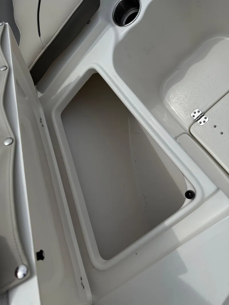 Slide: The Image of Key West 239 FS 2025 boat storage compartment with cup holder and seat hinge. - 16