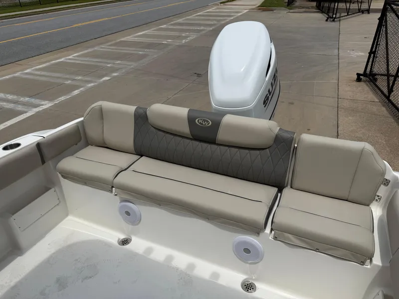 Slide: The Image of 2025 Key West 239 FS boat with cushioned seating and outboard motor, parked on pavement. - 21