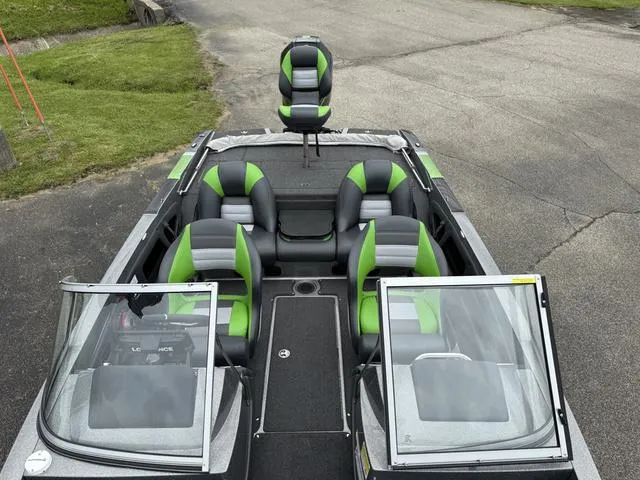 Slide: The Image of 2022 Ranger 212LS boat with green and gray seating, parked on pavement. - 6