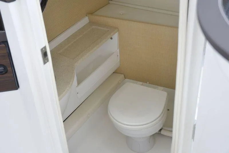 Slide: The Image of Compact bathroom in a 2017 Cobalt R7 boat, featuring a toilet and storage area. - 14