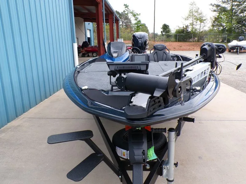 Slide: The Image of 2025 Skeeter ZXR21SE fishing boat on trailer, parked near a blue building. - 5