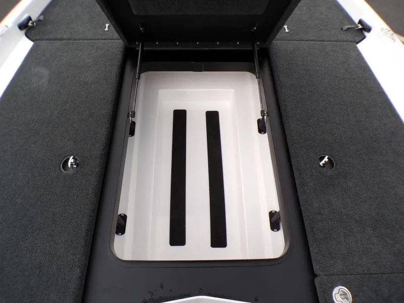 Slide: The Image of Open storage compartment on 2025 Skeeter ZXR21SE boat, featuring carpeted interior and hydraulic supports. - 16