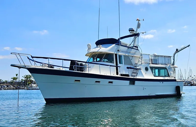 Slide: The Image of 1976 Hatteras 48 LRC yacht on calm water under a clear blue sky. - 0