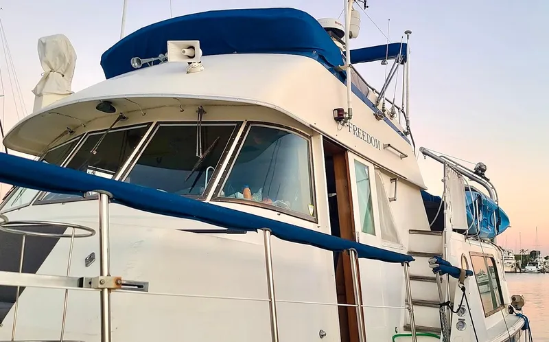 Slide: The Image of 1976 Hatteras 48 LRC yacht with blue accents docked at sunset. - 15