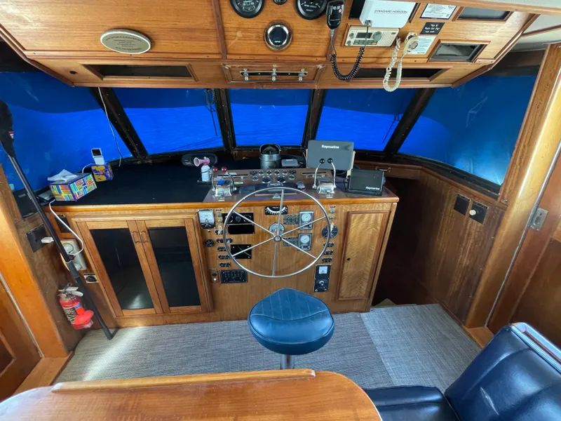 Slide: The Image of 1976 Hatteras 48 LRC helm with wooden dashboard, steering wheel, and blue seating. - 17