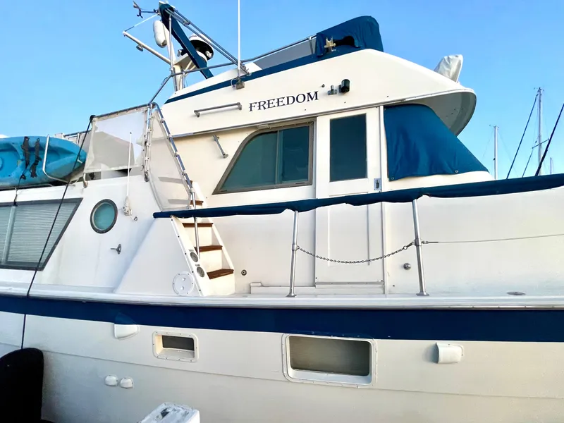Slide: The Image of 1976 Hatteras 48 LRC yacht with blue accents and upper deck, named "Freedom." - 2