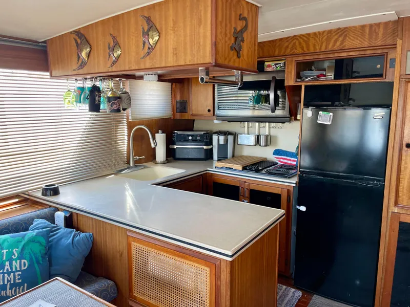 Slide: The Image of 1976 Hatteras 48 LRC yacht kitchen with wood cabinetry, modern appliances, and cozy seating area. - 22