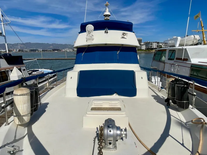 Slide: The Image of 1976 Hatteras 48 LRC yacht docked, featuring blue and white exterior under clear skies. - 3