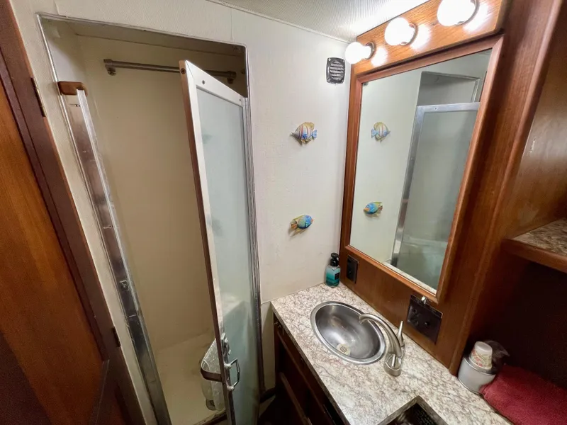 Slide: The Image of 1976 Hatteras 48 LRC bathroom with shower, sink, mirror, and decorative fish accents. - 37