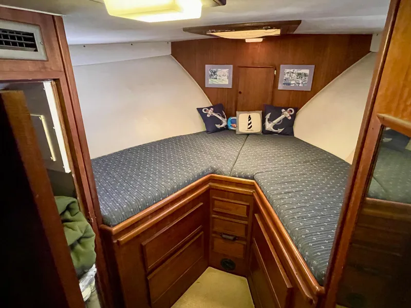 Slide: The Image of 1976 Hatteras 48 LRC cabin with V-berth, wooden cabinetry, and nautical-themed decor. - 39